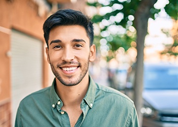 Man in green shirt walking down street and smiling