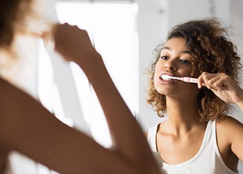 Dental implant patient in Midland brushing teeth