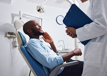 Smiling patient talking to dentist holding clipboard