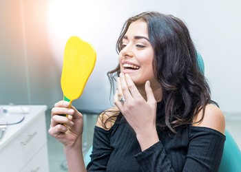 Woman smiling at reflection in handheld mirror